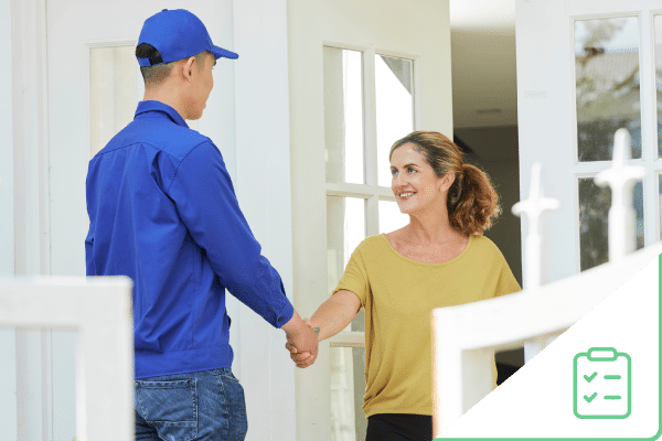 Construction worker shaking hand of woman at front door