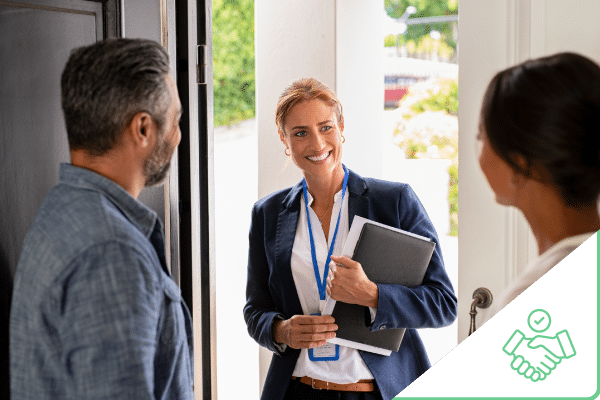 Couple talking to sales woman who is standing outside front door