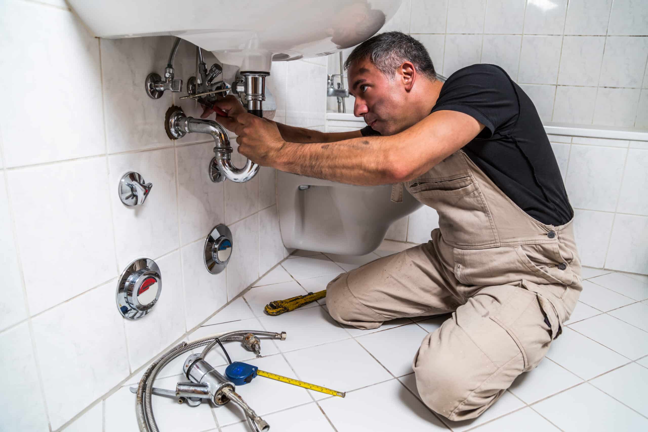 Plumber working on bathroom sink plumbing