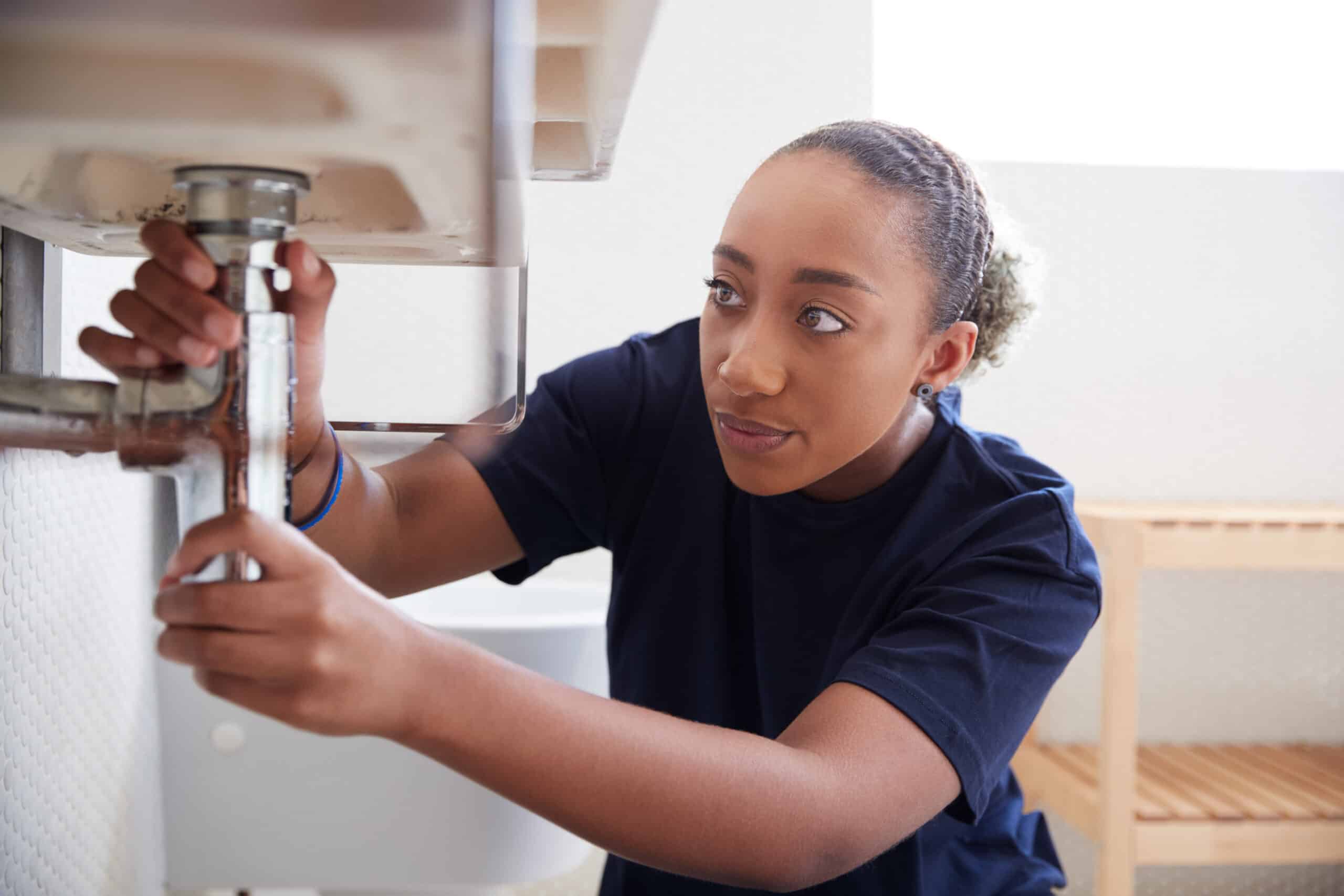 Female plumber working on sink plumbing