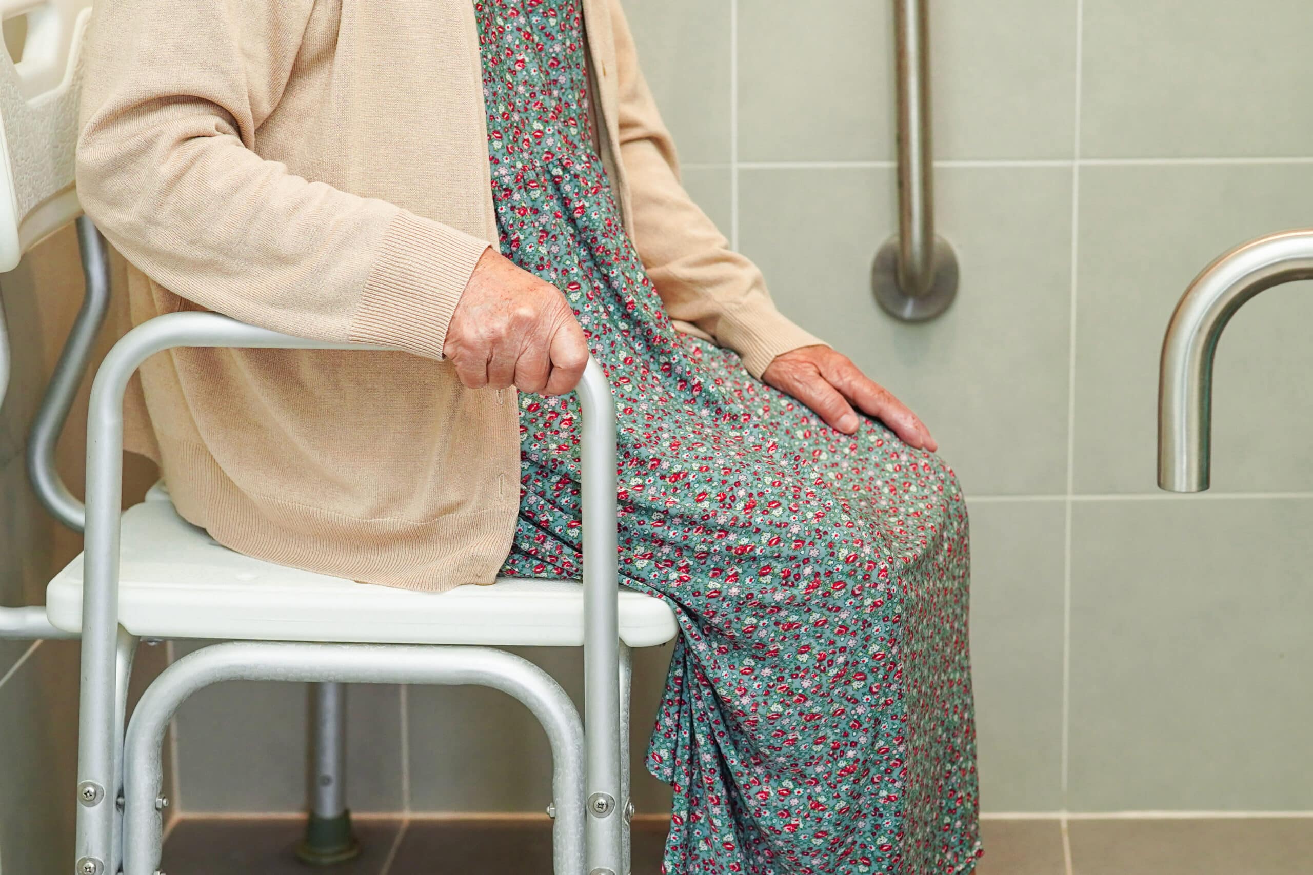 Older woman sitting on shower seat with grab bars in shower