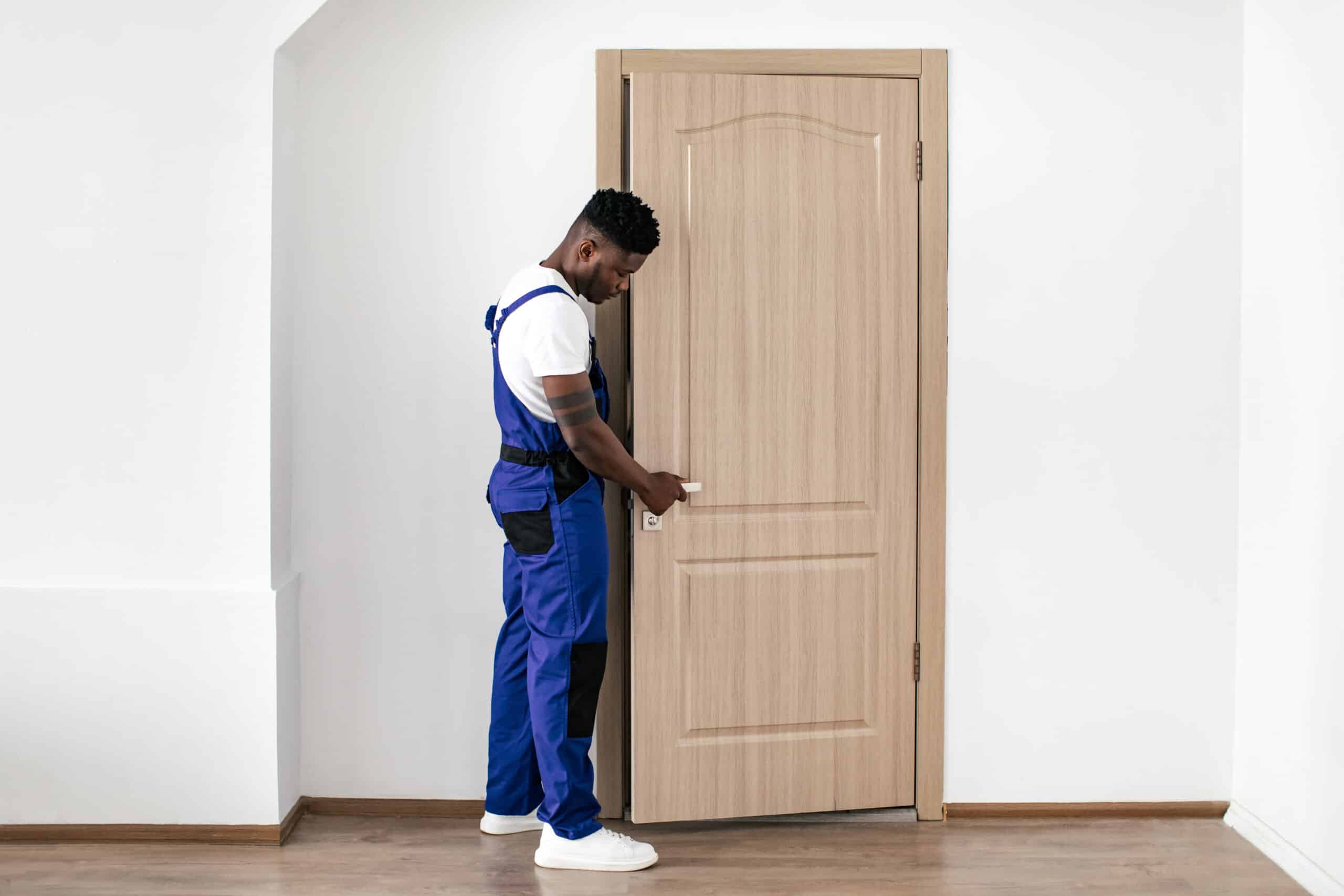 Black construction worker installing door in home