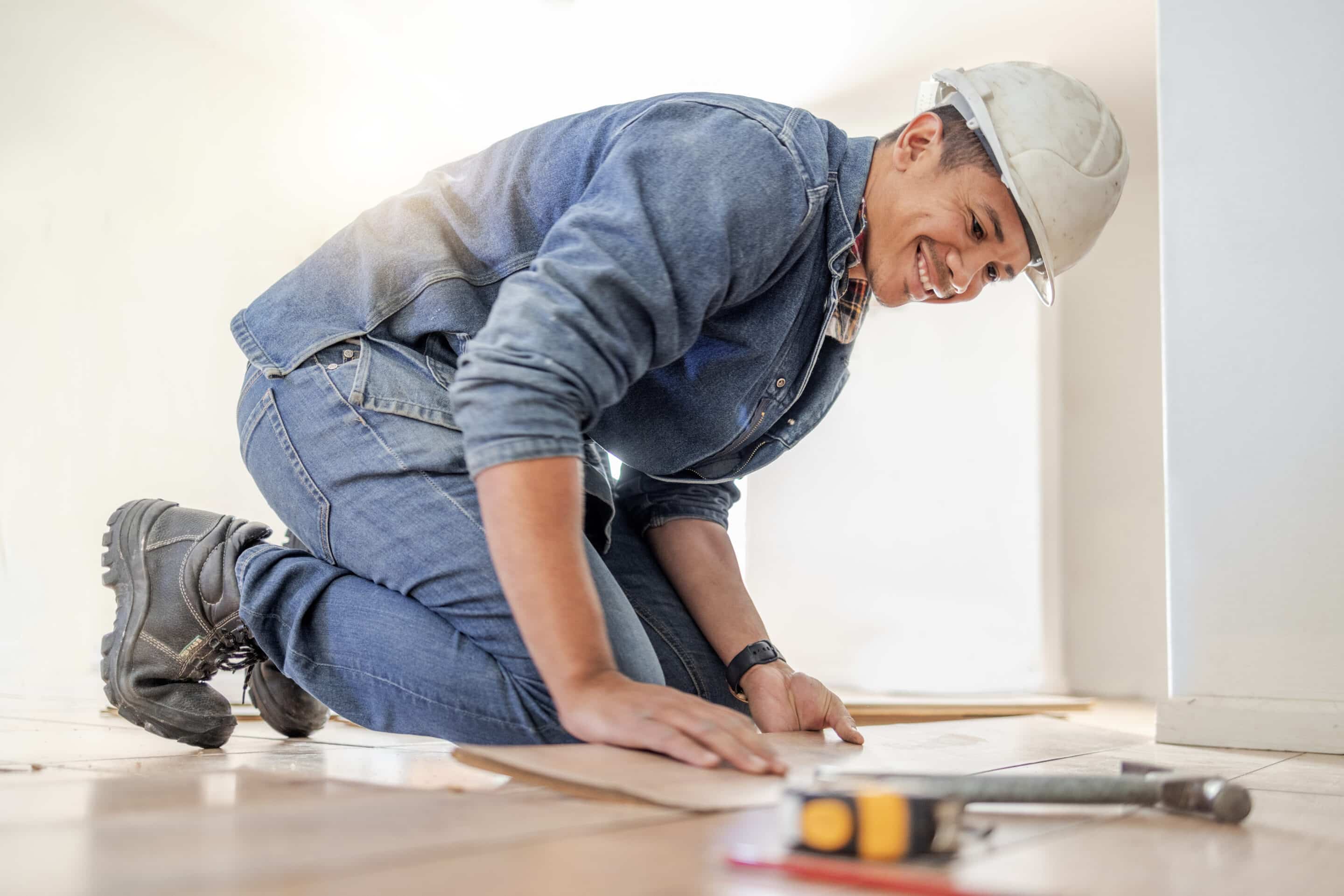 Diverse construction worker installing wood plank flooring