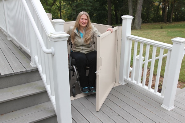 Woman in wheel chair using mobility lift to get up to outdoor deck