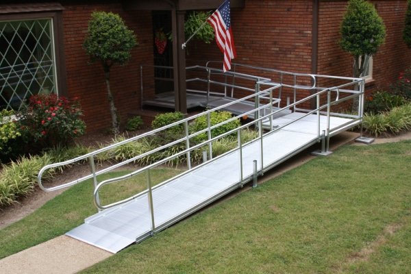 Man pushing woman in wheel chair up a ramp