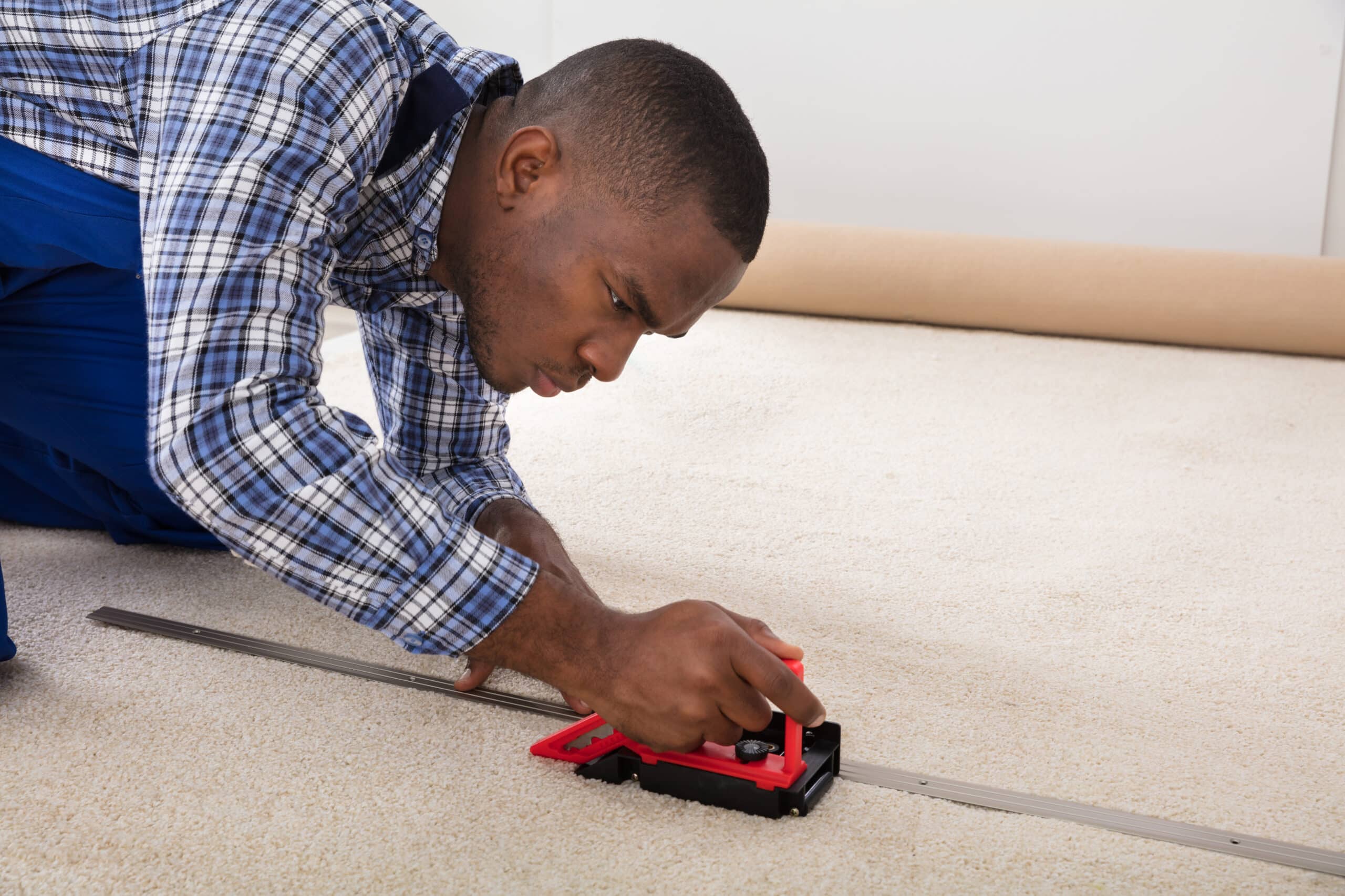 Black construction worker installing carpet in home