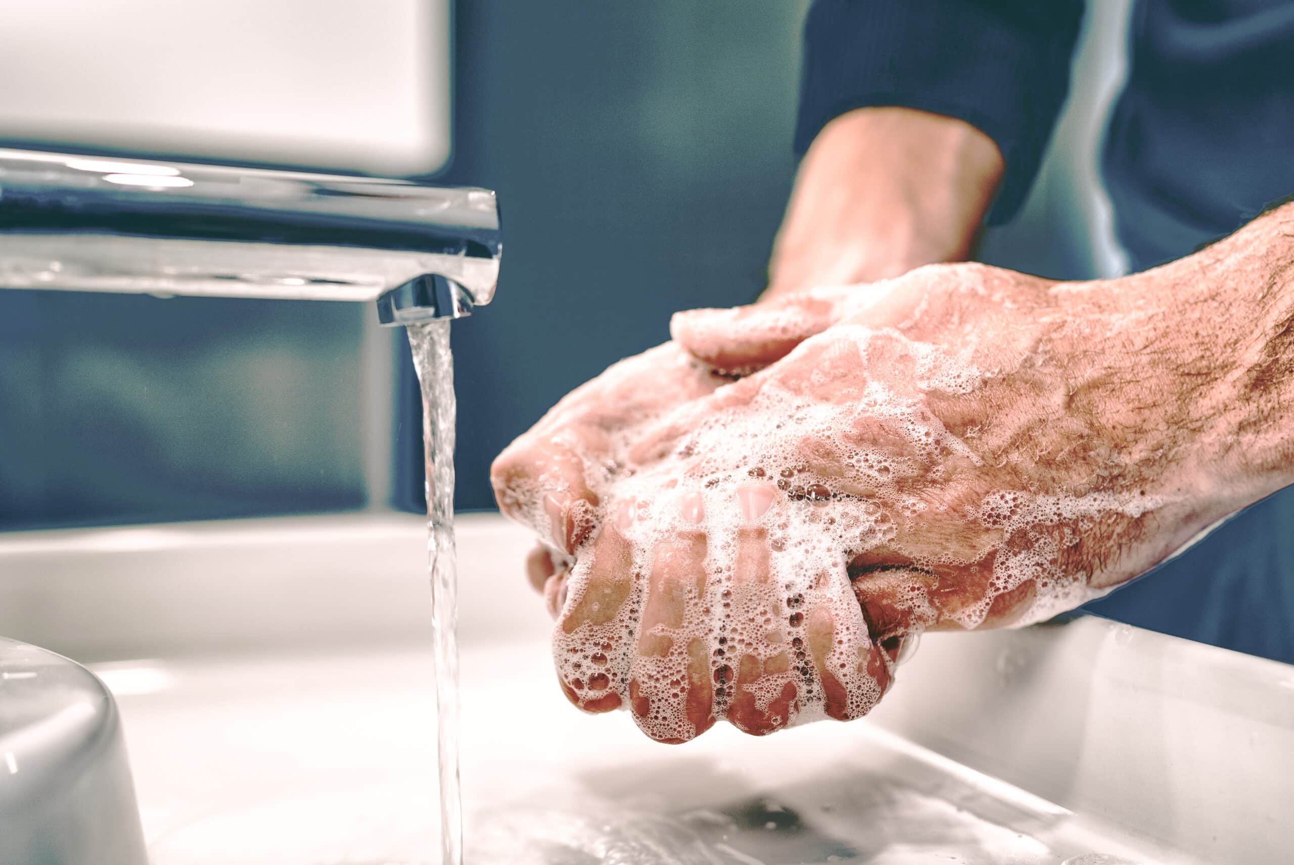 Older man washing hands using automated faucet