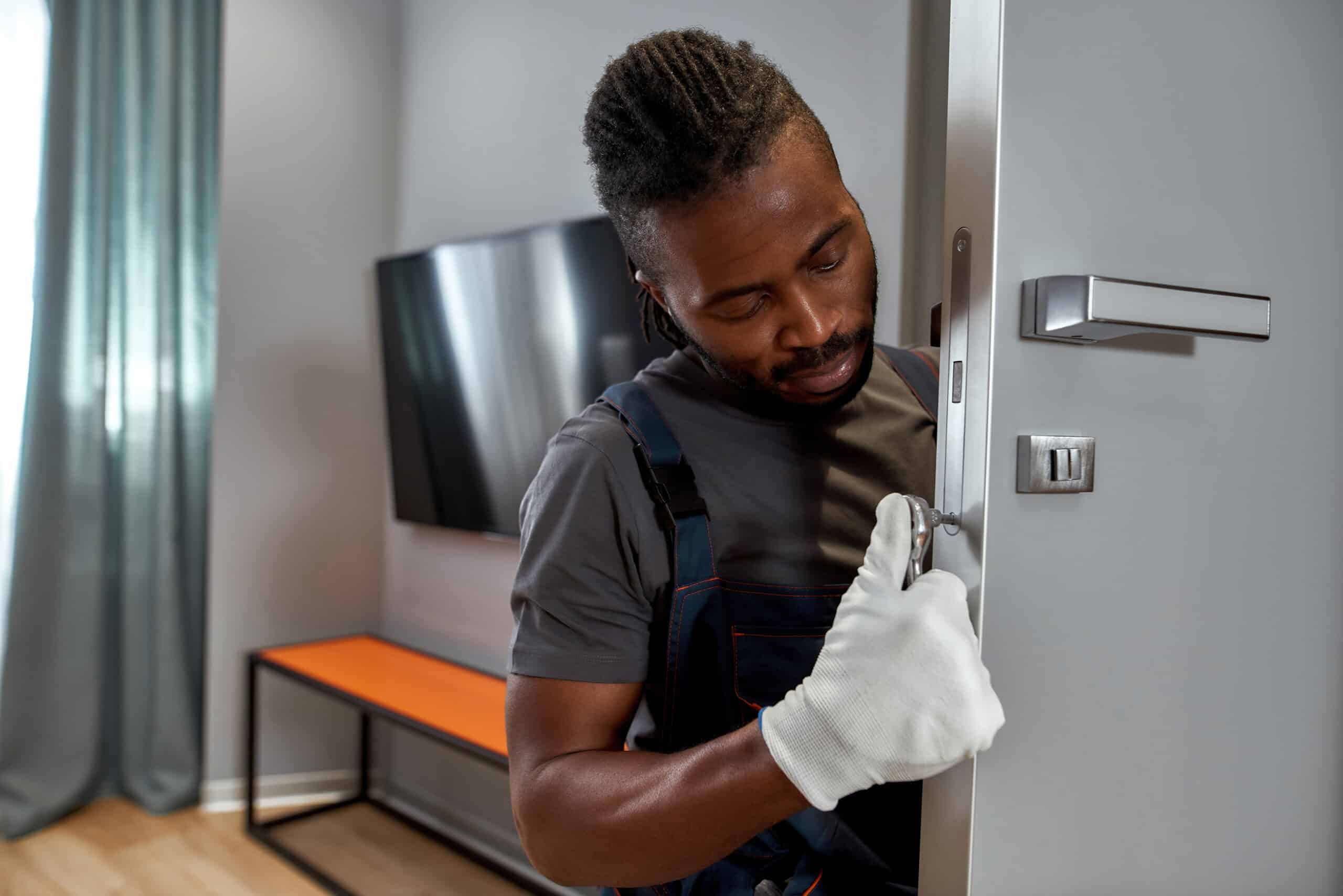 Black male construction worker installing new door in home